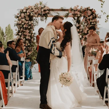 Bride and groom celebrating after breaking the glass at a Jewish wedding in Spain with petals and joy.