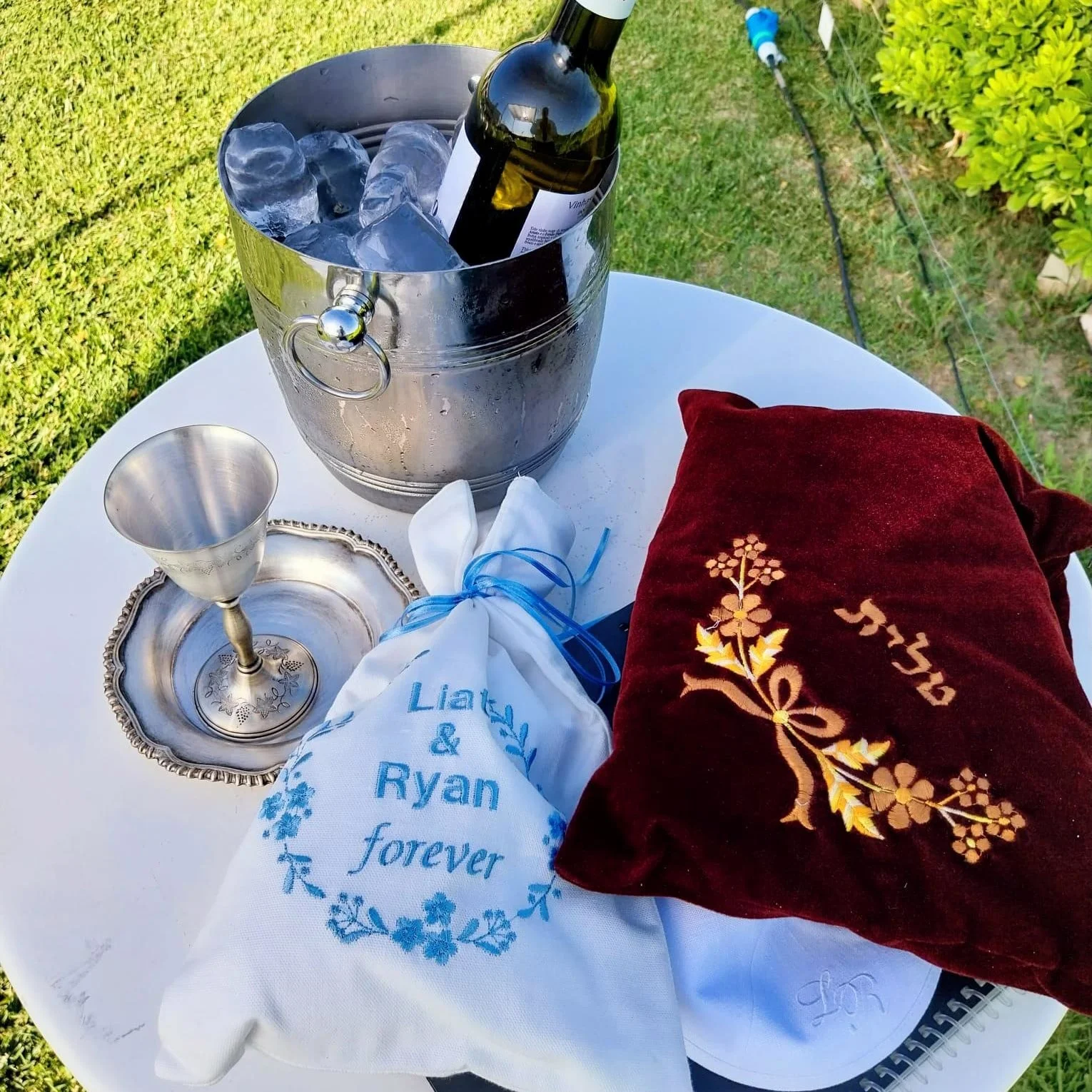 Mesa de rituales para boda judía en Casa Palmela: copa de Kiddush, vino y bolsa personalizada de Liat y Ryan para el rompimiento del vaso.